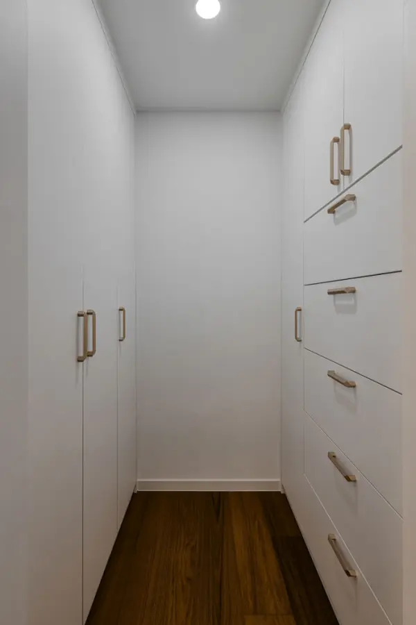 골드 손잡이로 포인트를 준 화이트 워크인 드레스룸